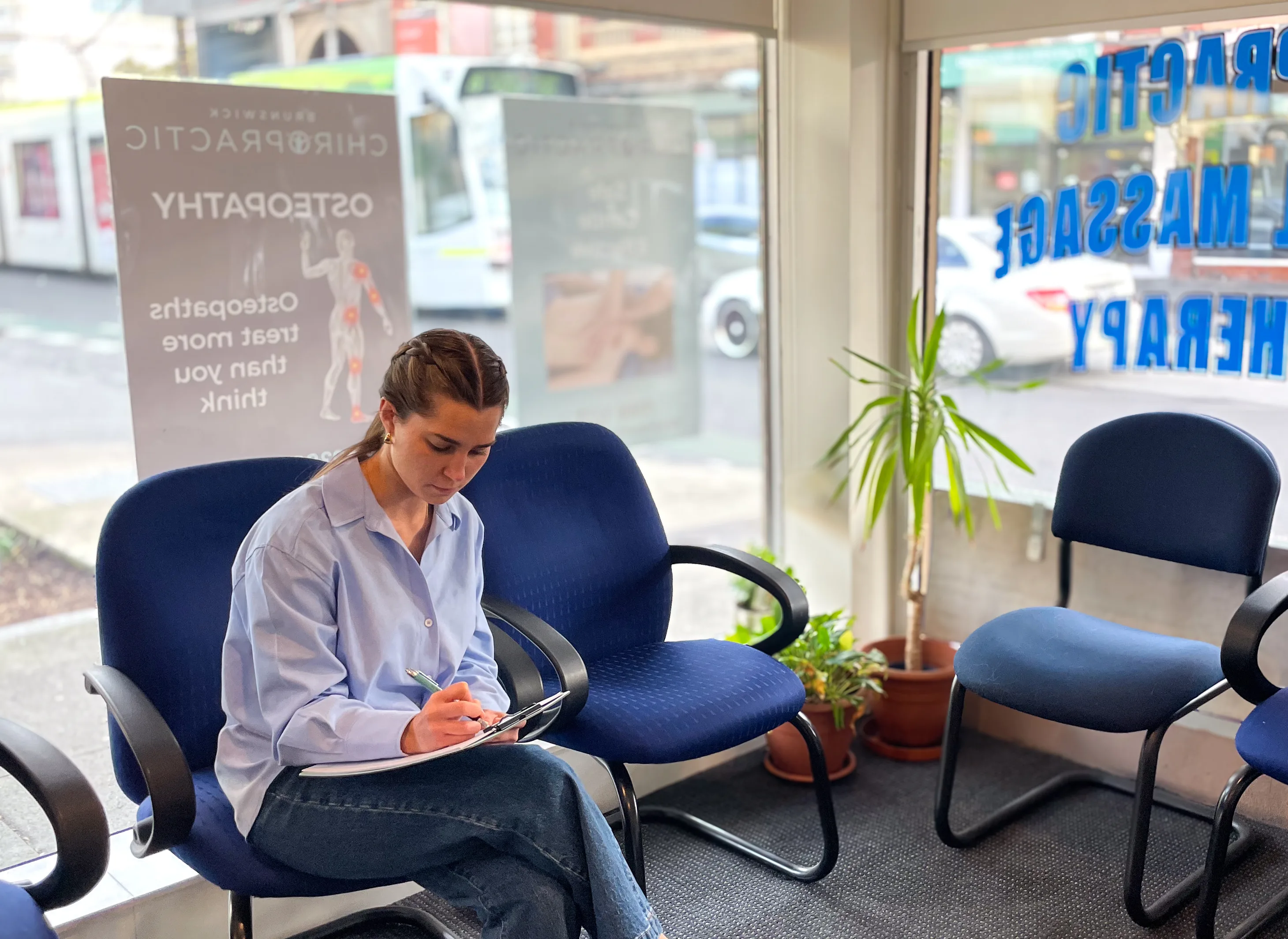 Brunswick Chiropractic waiting area — large shopfront windows with clinic decals, patient at reception